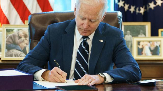 Biden at desk in Oval Office signing American Rescue Plan 