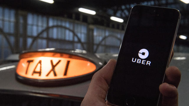 An Uber Technologies Inc. logo sits on a smartphone display in this arranged photograph at a taxi rank in London. 