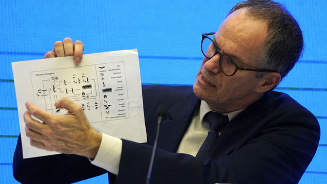 Peter Ben Embarek of the World Health Organization holds up a chart showing pathways of transmission of the coronavirus during a joint news conference at the end of a mission in Wuhan in central China's Hubei province February 9, 2021. 