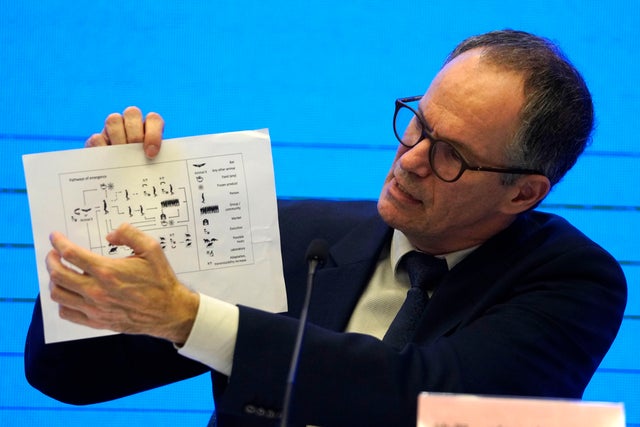 Peter Ben Embarek of the World Health Organization holds up a chart showing pathways of transmission of the coronavirus during a joint news conference at the end of a mission in Wuhan in central China's Hubei province February 9, 2021. 