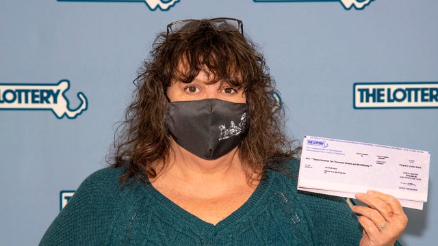 Lea Rose Fiega displays a winning lottery ticket March 30, 2021, at Massachusetts Lottery Commission headquarters in Boston. 