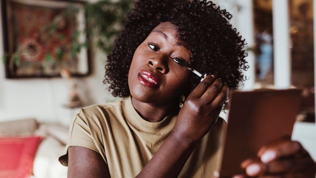 Mature Afro woman applying mascara at home 