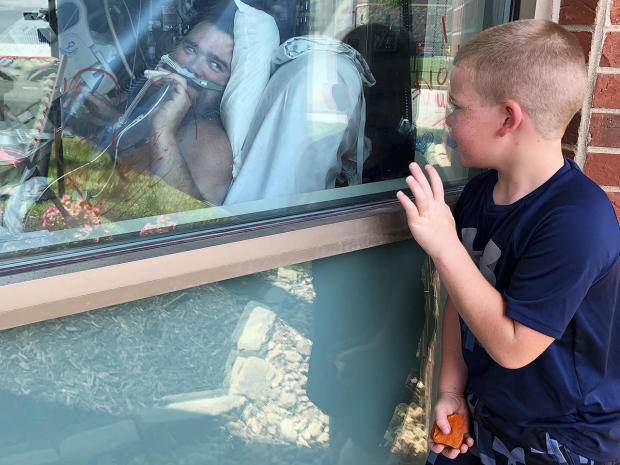 Six-year-old Brody Barker waves to his father, Daryl, from outside his hospital room July 26, 2021, in Osage Beach, Missouri, where Daryl has been hospitalized for nearly three weeks for COVID. Daryl told reporters he had resisted getting vaccinated. 