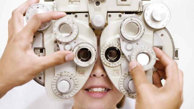 Optometrist (optician) examining eye of woman 
