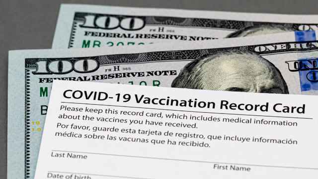 Covid-19 vaccination record card and cash money. Fake, vaccine card fraud and forgery concept 