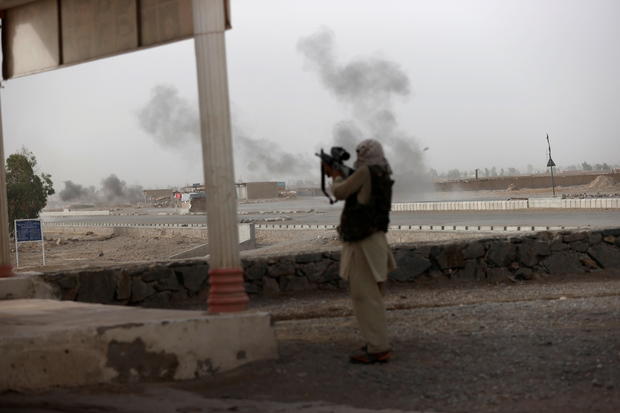 An Afghan soldier holds a gun and looks towards Taliban positions as smoke rises in the distance from clashes on the outskirts of Spin Boldak in Kandahar province, Afghanistan 