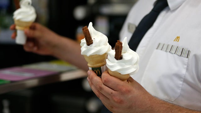 Three ice cream cones held by worker 