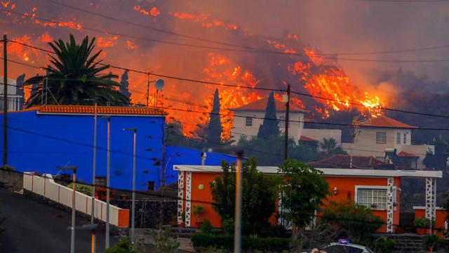 Lava flows behind houses following the eruption of a volcano in Spain 