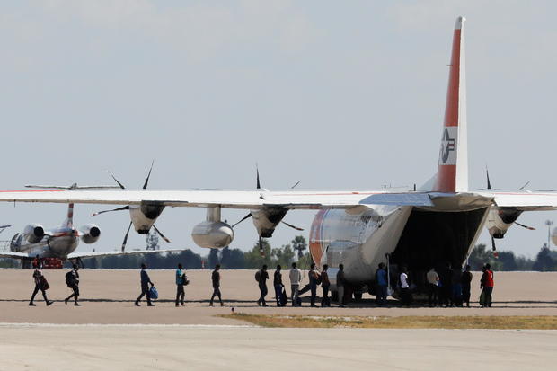 Migrants board a U.S. Coast Guard airplane at the Del Rio International Airport as U.S. authorities accelerate removal of migrants at border with Mexico, in Del Rio 
