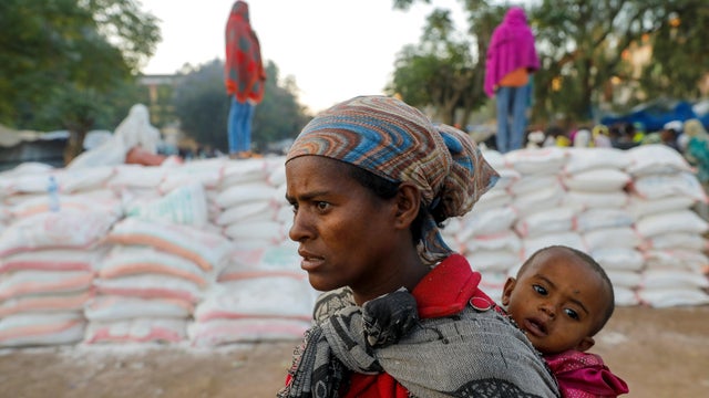 Woman carries an infant as she queues in line for food in Tigray region of Ethiopia 