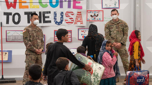 U.S. Military Police walk past Afghan refugees at the Village at Fort McCoy U.S. Army base 