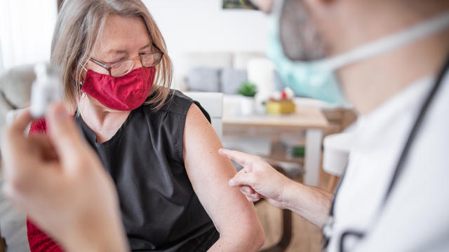 Booster dose vaccine Covid 19. The doctor gives the vaccine to an older woman. 