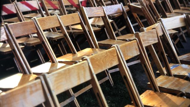 Rows of empty wooden chairs outdoor graduation 