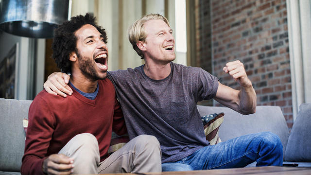 Two friends watching sports on tv 