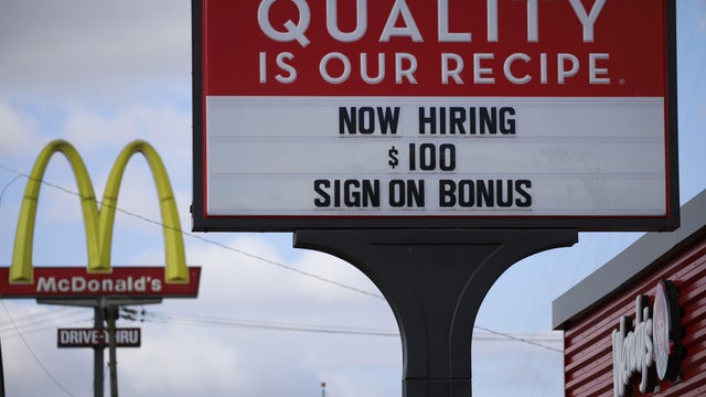 "Now hiring" sign with McDonald's sign in background 