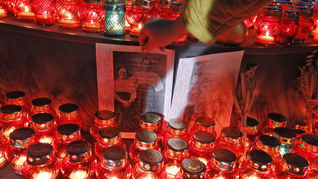 A woman places her family photo at the monument of victims 