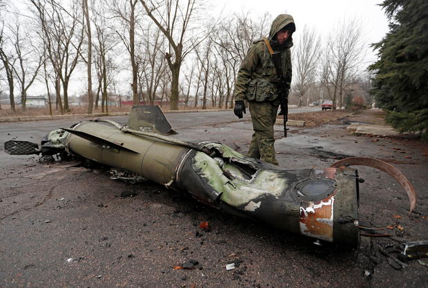 A militant of the self-proclaimed Donetsk People's Republic inspects the remains of a missile that landed on a street in Donetsk 