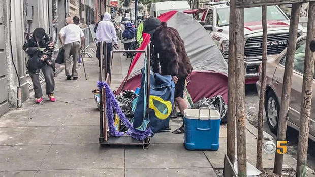 An Unhoused Person Moves a Tent on a Sidewalk in San Francisco's Tenderloin District 