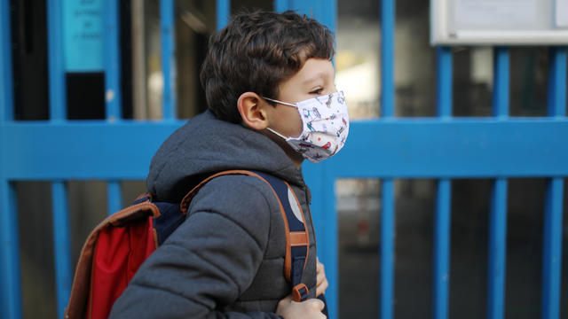 Portrait of a boy wearing a protective face mask in front of school 