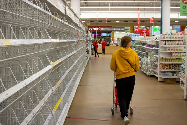 A woman walks by empty shelves in a supermarket in Moscow. 