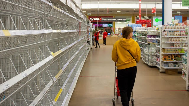 A woman walks by empty shelves in a supermarket in Moscow. 