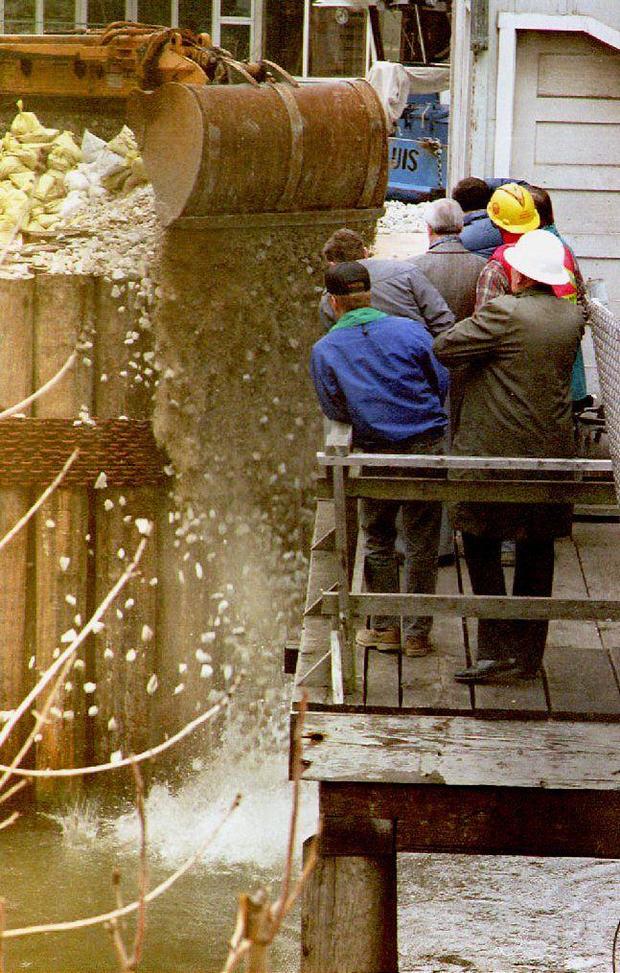 Workers pour gravel in an attempt to block a hole 