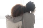Loving african single mother embrace teen daughter sit on bed 
