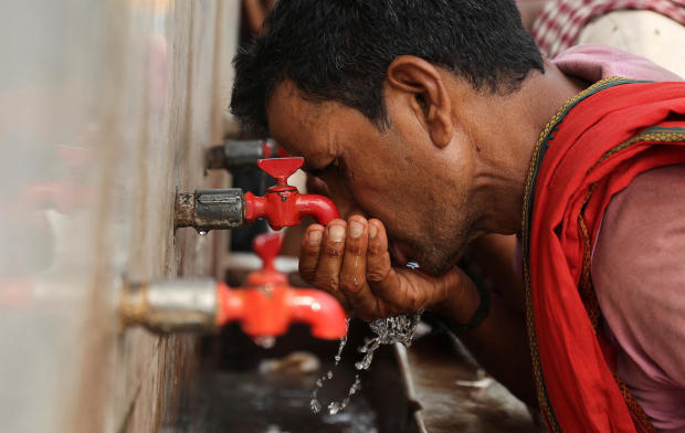 A laborer drinks from a public drinking water tap on a hot day in the old quarters of Delhi, India, May 4, 2022. 