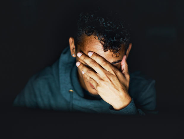 mental health depression  Young man sitting in the dark covers his face 