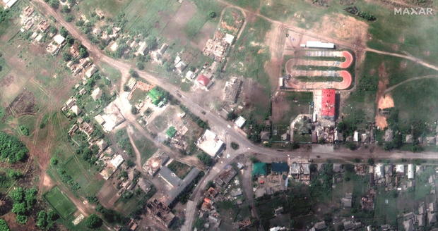 A satellite image shows damaged buildings and a tank on a road, in Lyman 