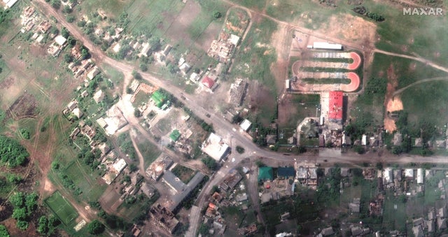 A satellite image shows damaged buildings and a tank on a road, in Lyman 