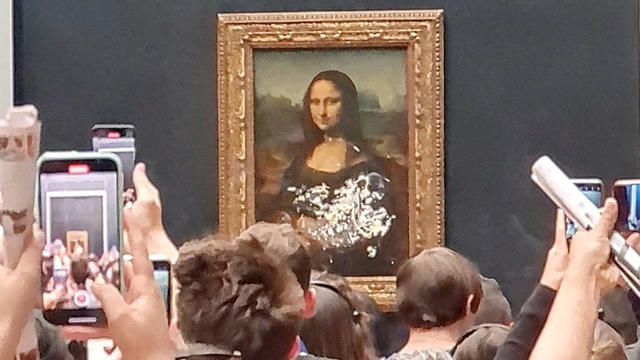 Visitors take a pictures and video of the painting "Mona Lisa" after cake was smeared on the protective glass at the Lourve Museum in Paris 