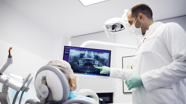 Dentist explaining X-ray to patient at clinic 