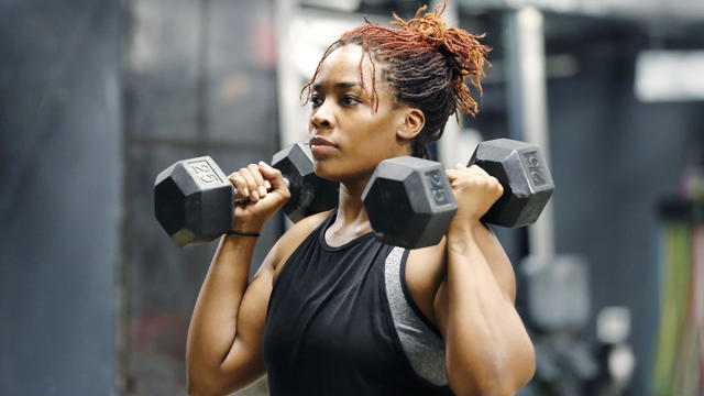 Fit, young African American woman working out with hand weights in a fitness gym. 