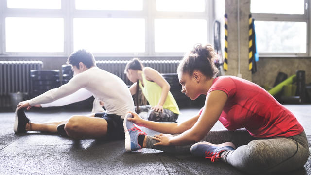 Three young people stretching in gym 