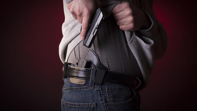 A person concealing their pistol on their hip 