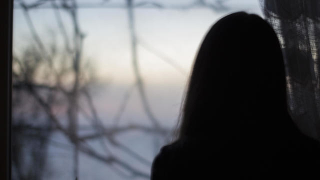 Silhouette of a woman looking out a window 