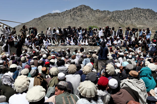 Afghan people wait to receive aid in an area affected by an earthquake in Gayan 