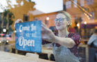 Business owner setting up open sign in cafe window 