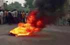 Smoke rises from a burning material while people gather on road as tensions rise after killing of a Hindu man, in Udaipur 