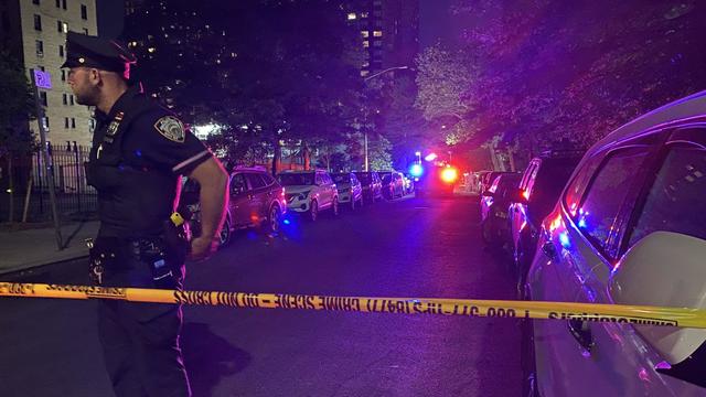 A police officer stands behind police tape blocking off a street on the Upper East Side 