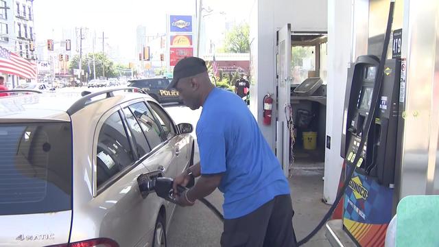 A gas station attendant pumps gas for a customer at a Sunoco station. 