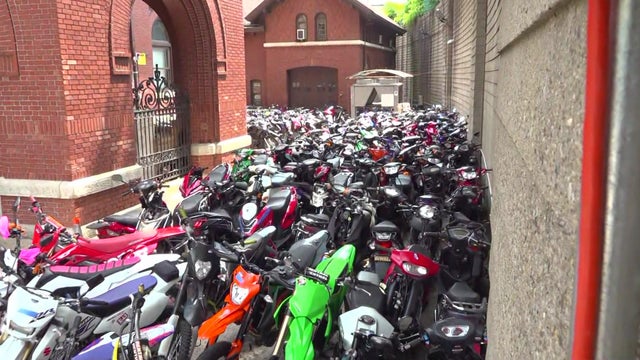 Hundreds of illegal ATVs and dirt bikes parked in an alley. 