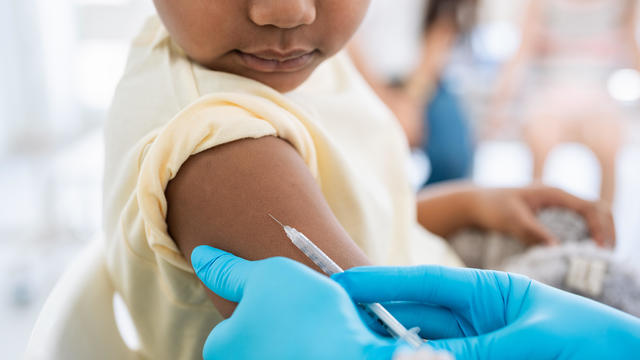 Immunisation. Protecting children from diseases. Close-up nurse in medical gloves giving injection to little patient. Brave boy getting a flu shot at doctor's office and looking at needle 