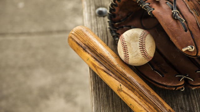 Baseball season is here.  Bat, glove and ball on dugout bench. 