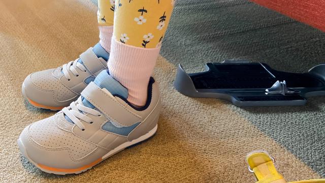 young girl tries on new sneakers for school in store 