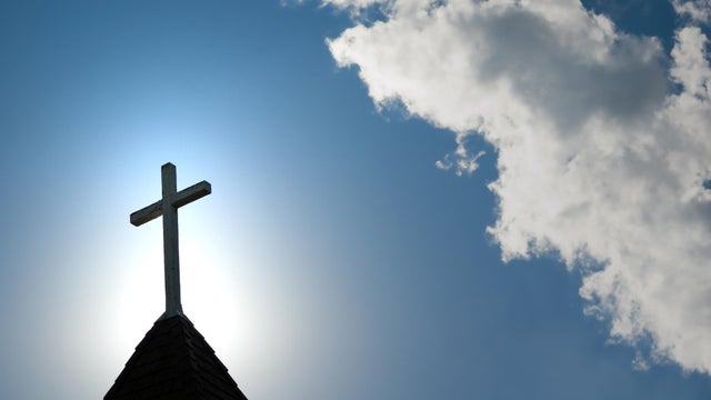 Easter morning with the sun behind a church steepl cross. 