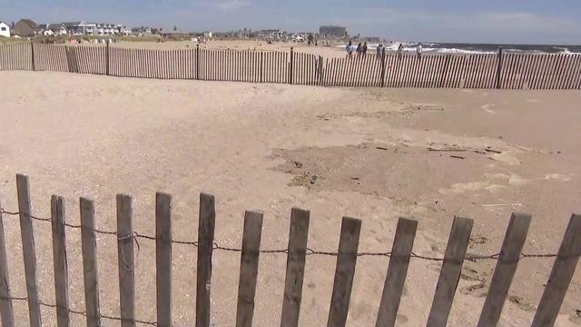 A section of sand on a beach is fenced off due to a sinkhole. 