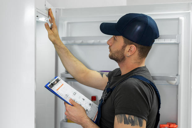 Young technician checking refrigerator 
