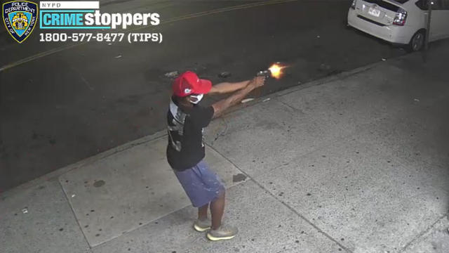 Surveillance photo shows a man firing a gun on a sidewalk. 